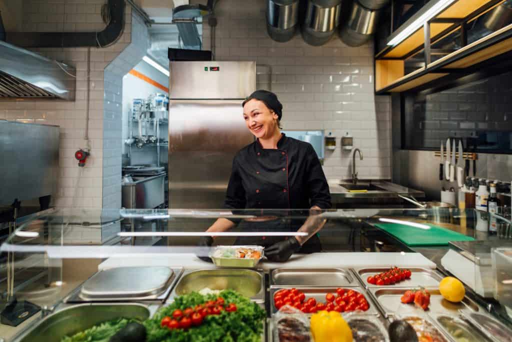 Joyful cafe worker prepares salad. Catering kitchen work