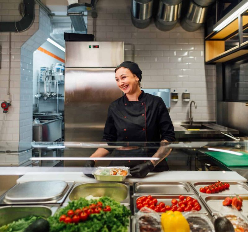 Joyful cafe worker prepares salad. Catering kitchen work