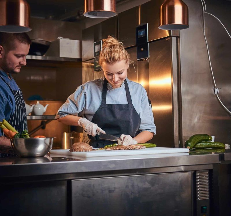 Male chef with assistant standing in a kitchen, preparing food in a luxury restaurant